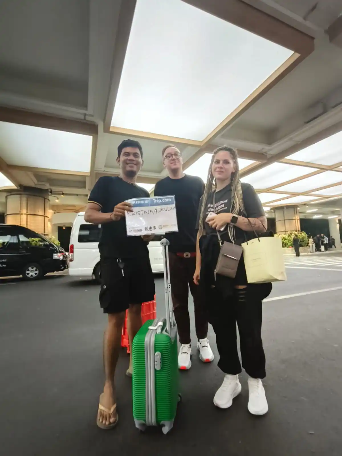 A friendly Bali private driver assisting travelers as they enter the vehicle for their tour.